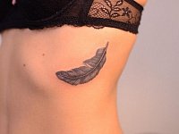 Женская тату перышко на ребрах