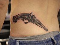 Тату на пояснице револьвер