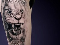 Тату лев с оскалом на бедре